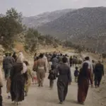 گروهی از مردم در حال حرکت در جاده‌ای کوهستانی در کردستان